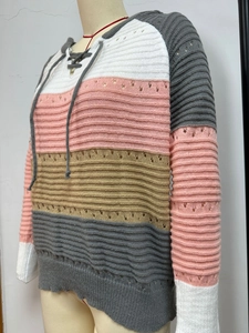 Detail of color-block striped knit sweater featuring hollow-out patterns and V-neck drawstrings