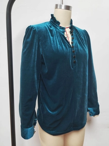 Détail du col montant à volants et boutons sur une chemise en velours bleu sarcelle