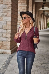 Dettaglio maglione a coste bordeaux con scollo a V e zip dorata regolabile