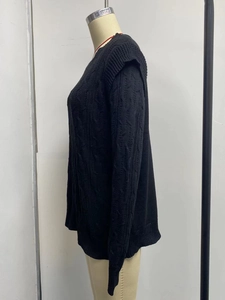 Detailed close-up of a black chunky cable knit sweater featuring a loose-fitting design