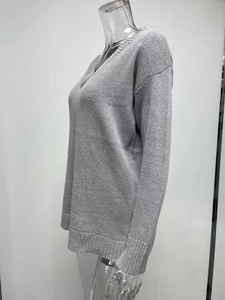 Close-up of light grey V-neck knit sweater showing ribbed cuffs and drop shoulder texture