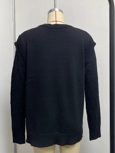 Close-up of black cable-knit sweater with vertical textures and ribbed cuffs and hemline