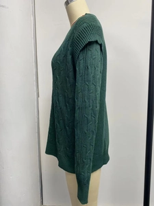 Detailed macro view of heavy knit cable stitch pattern on dark green sweater sleeve
