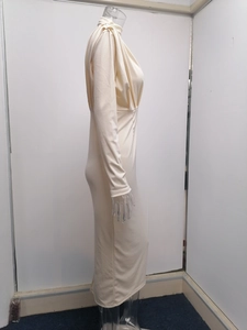 Detailweergave van crèmekleurige jurk met lange mouwen, tailleplooien en gedrapeerde halslijn