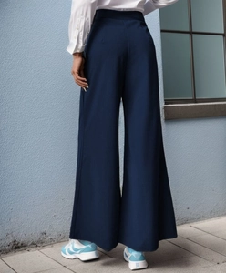 Détail montrant le drapé élégant et la taille haute du pantalon large bleu marine