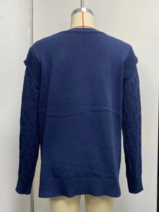 Detail view of the back of a dark blue cable knit sweater with ribbed cuffs and hem
