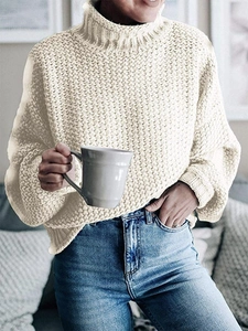 Detail eines beigen Grobstrick-Rollkragenpullovers mit Rippkragen und warmer Textur