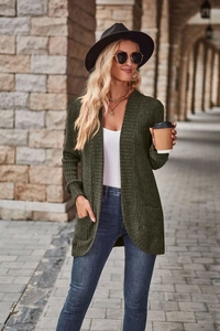 Detail of dark green waffle knit cardigan showing long sleeves and functional side pockets