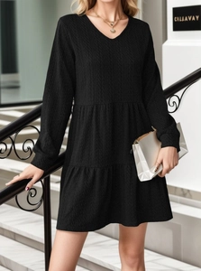 Detail of V-neck black long sleeve tiered dress with textured fabric on a model