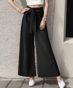 Détail du pantalon large à taille haute avec une ceinture à nouer en nœud papillon noir