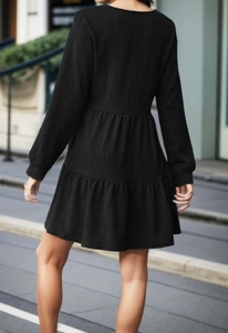 Detail of black tiered long sleeve dress with textured fabric and ruffled A-line hem