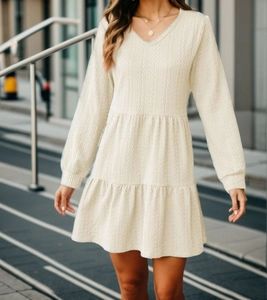 Detail of cream V-neck long sleeve dress featuring textured cable knit fabric and tiered hem