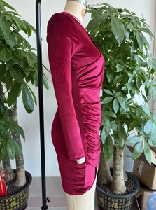 Détail latéral d'une robe en velours bordeaux avec des fronces et une coupe ajustée