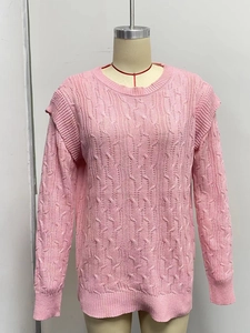 Detail of pink knitted sweater showing classic cable stitch and ruffle trim on shoulders
