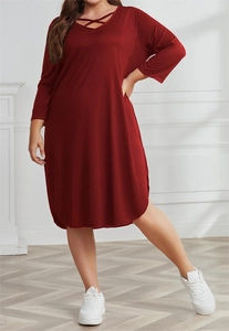 Detail of cross-strapped neckline on a loose burgundy plus size long-sleeve dress