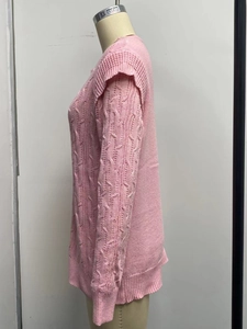 Detail of pink cable-knit sweater showing textured shoulder frill and ribbed sleeve cuff