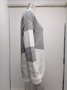 Detailed side view of loose knit sweater featuring grey and white color-block patterns