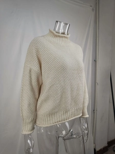 Detalle de jersey de punto grueso crema con textura granulada y puños acanalados