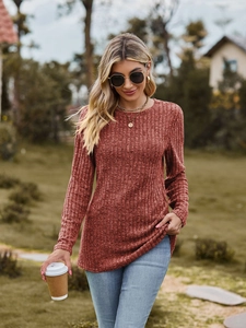 Detail of rust red ribbed knit long sleeve top showing the soft textured fabric and crewneck