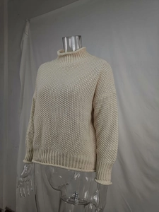 Detalle de jersey de punto grueso color crema con cuello alto y textura de punto acanalado