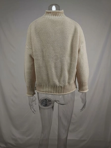 Vista trasera de jersey de punto grueso oversize en color beige con cuello alto tipo cisne