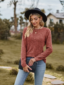 Detail of brick red long sleeve knit top with vertical ribbed texture in outdoor garden