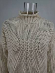 Primer plano del tejido grueso en este suéter de cuello alto en color crema