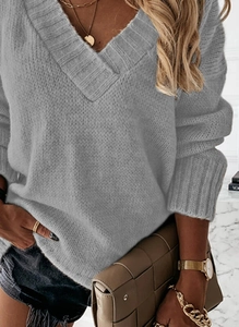 Detailed view of grey V-neck knit sweater showing thick ribbed cuffs and coarse texture