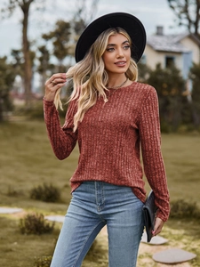 Detail of rust red ribbed knit long sleeve top paired with blue jeans and accessories