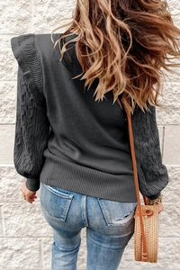 Close-up of charcoal grey knit sweater featuring ruffled shoulders and cable knit sleeves