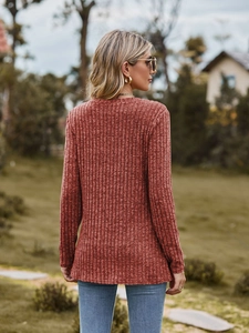 Detail of rust red long sleeve knit top with ribbed texture and slim fit round neck