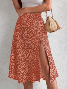 Detail view of brick red floral midi skirt featuring a high slit and daisy pattern