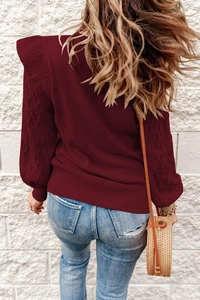 Close-up of wine red cable knit sweater featuring detailed braided sleeve texture