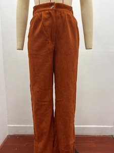 Detail of high-waist orange corduroy pants featuring vertical texture and resin button