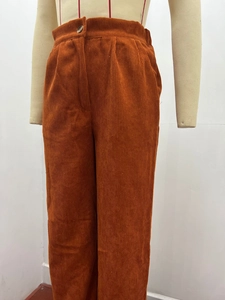 Detail of high waist corduroy pants in caramel brown with button and pleated waist design