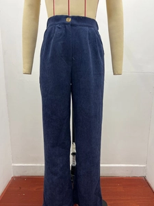 Detailed close-up of dark blue corduroy trousers with high-waist button and ribbed texture