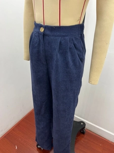 Detail of navy blue corduroy fabric texture and high-waist pleats with vintage button