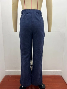 Detail view of the elastic high waist and ribbed corduroy texture on dark blue trousers