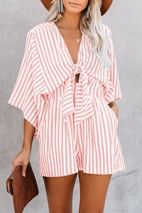 Detail of pink striped summer romper with a deep V-neck, waist tie, and convenient pockets