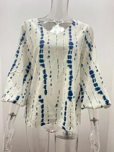 Detailansicht der weißen V-Ausschnitt Bluse mit blauen Batikstreifen und ausgestellten Ärmeln