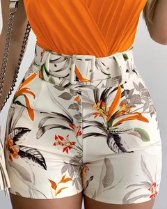 Detail of high-waisted floral shorts with matching belt and orange V-neck camisole top