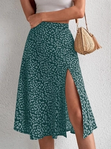 Detail view of floral midi skirt with side slit and white daisy pattern on dark green fabric