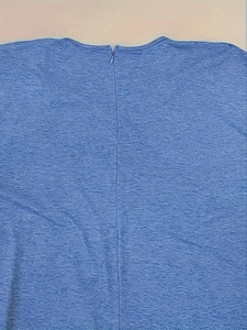 Detail view of the seamless invisible zipper on the textured blue V-neck jumpsuit fabric