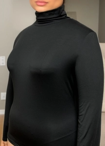 Close-up of black turtleneck long sleeve top showing tight fit and elastic fabric detail