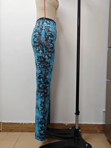 Detail view of high-waisted flared trousers with blue and black artistic floral print