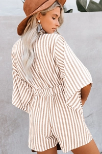 Outdoor street view of a bohemian vertical striped romper with waist-defining cut