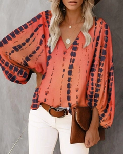Detailaufnahme der orangefarbenen V-Ausschnitt Bluse mit blauen Batik-Streifen Mustern