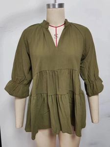 Detail of olive green tiered babydoll top featuring textured fabric and V-neckline