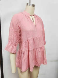 Detail view of pink V-neck tiered top with pleated ruffles and elastic puff sleeves