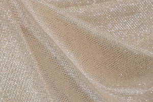 Detail of shimmering champagne mesh fabric with metallic glitter threads on the dress